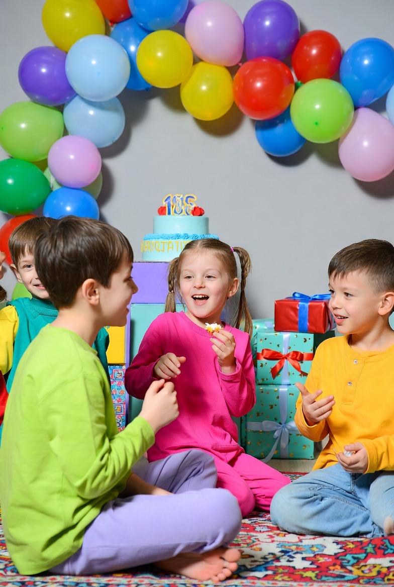 Kids at a birthday party with balloons and presents